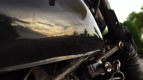 Nahaufnahme-Des-Schiebereglers-Eines-Motorradtanks,-Der-Den-Sonnenuntergang-Widerspiegelt