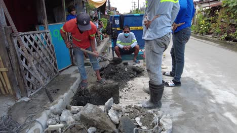 Foremen-wearing-safety-reflective-vests-used-their-shovel,-mixed-cement,-and-demolition-hammer-to-perform-excavation-beside-the-road-gutter-to-install-new-water-piping-from-the-main-water-line