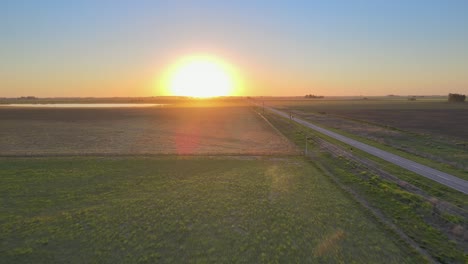 Road-running-through-the-Pampas-in-La-Pampa,-Argentina,-sunset-drone