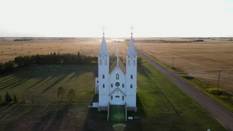 Frontal-Aerial-view-of-roman-catholic-church-in-north-American-prairie-during-sunset