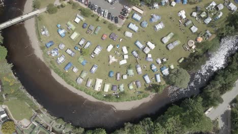 Aerial-View-Of-Camping-Tents,-Campervans-And-Caravans-On-The-Riverbank-Of-River-Avonmore-In-Rathdrum,-Wicklow,-Ireland