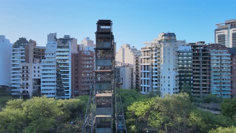 Slow-pan-shot-capturing-the-rustic-details-of-around-the-world-ferris-wheel-against-rows-of-residential-apartments-along-av