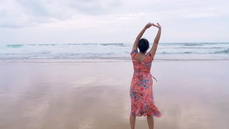 Young-Asian-woman-admiring-the-beauty-of-the-ocean-and-stretching-her-body-breathing-fresh-air