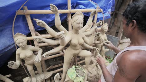 Poor-artisan-doing-finishing-touches-to-idols-of-Hindu-goddess-Durga-with-clay-at-Kumartuli,-slow-motion-track-zoom-in-shot