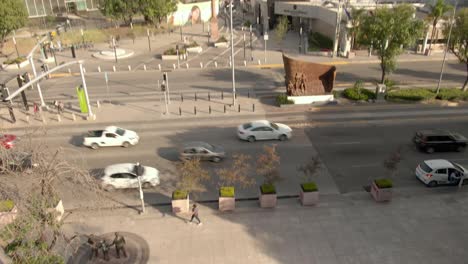 Tráfico-Conduciendo-En-La-Carretera-Entre-La-Plaza-De-La-Familia-Y-El-Jardín-De-Los-ángeles-Con-El-Monumento-A-Colón-En-Santiago-De-Querétaro,-México