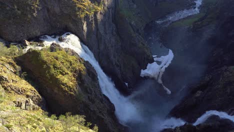 Spectacular-Vøringsfossen-waterfall-in-dramatic-landscape-Hardangervidda-Norway---Static-shot-of-waterfall-during-beautiful-sunset-with-water-spashing-far-down-in-the-canyon