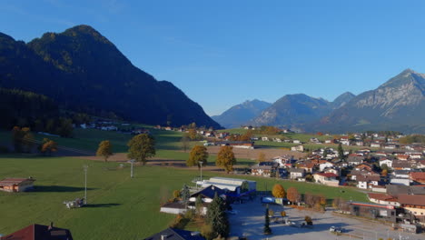 Breathtaking-calm-flight-towards-mountains-above-town-in-Austria,-drone-push-in