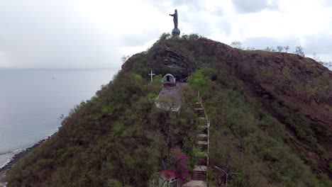 Aerial-drone-view-of-the-popular-Cristo-Rei-Jesus-Christ-statue,-popular-international-and-domestic-tourist-hotspot,-on-tropical-island-of-Timor-Leste,-South-East-Asia
