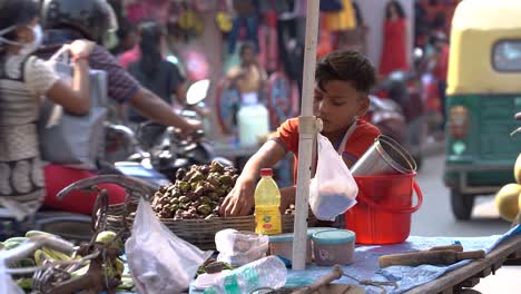 Poor-orphan-child-fruit-seller-selling-fruits-on-street,-vehicles-passing-by