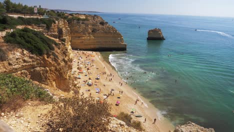 Slowmotion-of-Marinha-Beach-and-Blue-Sea-in-Portugal-with-Tourists-Chilling-on-the-Beach-during-Sunny-Weather
