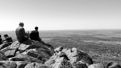 Hikers-sitting-on-a-high-rock-ledge-overlooking-the-landscape-below