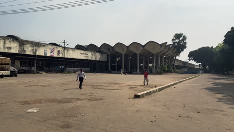 View-Behind-Kamalapur-Railway-Station-Empty-Car-Park-And-Side-Access-Road-With-People-Walking-Past-In-Dhaka