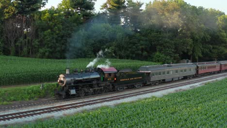 Strasburg-Railroad-steam-locomotive-travels-through-rural-farmland-at-golden-hour