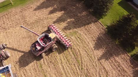 Combine-Harvester-Harvesting-Ripe-Corn-On-Harvest-Field-In-Michigan---aerial-drone-shot