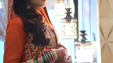 Asian-Brides-Hands-Clasped-Covered-In-Beautiful-Henna-Design-Wearing-Orange-Wedding-Outfit