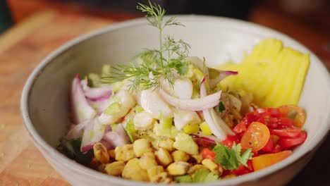 Cinematic-close-up-shot-of-delicious-peruvian-seafood-salad,-ceviche-starter-dish-with-heathy-and-colorful-freshly-prepared-ingredients-and-garnished-with-leafy-fennel-fronds
