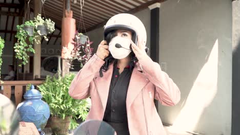 Woman-take-and-put-on-safety-helmet-to-ride-motorbike,-handheld-motion-view