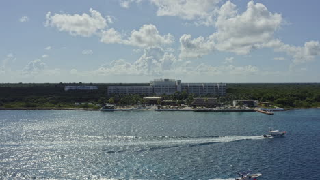 Cozumel-Mexico-Aerial-v2-drone-fly-away-from-fiesta-americana-contemporary-resort-overlooking-at-caribbean-sea,-with-two-speed-boats-cruising-in-the-foreground-with-water-wakes---September-2020
