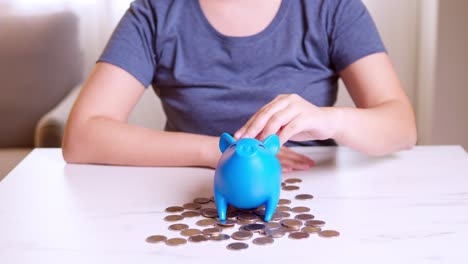 Saving-money-concept,-Asian-woman-hand-putting-money-coin-into-piggy-bank