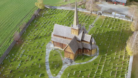 Paisaje-Verde-Del-Cementerio-Con-La-Iglesia-De-Madera-De-Lom-En-El-Municipio-De-Lom,-Condado-De-Innlandet,-Noruega