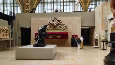 Orsay-museum-in-Paris-with-statues-and-some-visitors-on-the-ground-floor-of-the-gallery