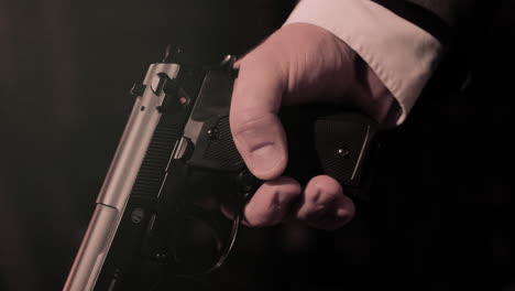 Close-up-on-mafia-man-in-suit's-hands-holding-a-pistol