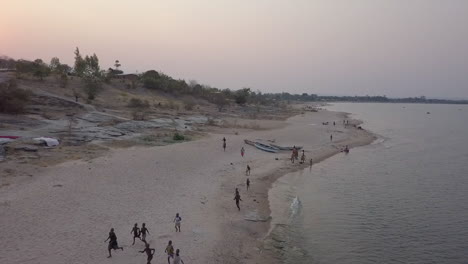 Fröhliche-Tumbuka-Kinder-Eilen-Am-Ufer-Des-Malawi-Sees-In-Richtung-Drohne