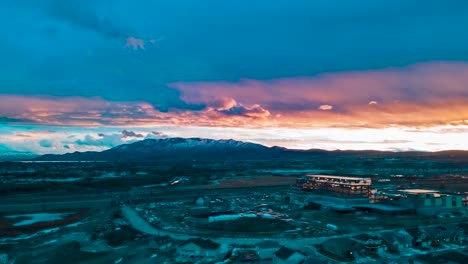 Colorful-sunset-over-the-mountains-in-an-urban-suburb-in-winter---aerial-hyper-lapse