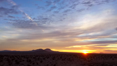Perfect-romantic-view-of-the-Mojave-Desert-during-a-golden-sunset-or-sunrise---pull-back-wide-angle-scenic-view-with-the-mountains-in-silhouette