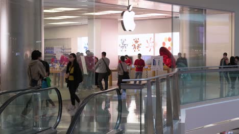 People-walk-past-the-multinational-American-technology-brand-official-Apple-store-and-logo-at-a-shopping-mall-in-Hong-Kong
