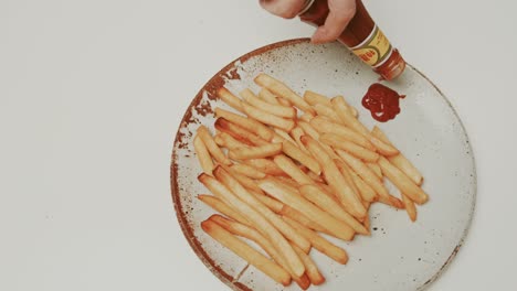 Adding-delicious-red-color-ketchup-to-golden-french-fries-on-a-big-plate