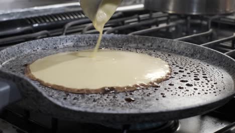 Ladle-spoon-pours-pancake-batter-on-hot-oil-on-pan,-hotcake-breakfast,-close-up