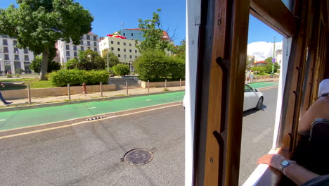 Touristen,-Die-Die-Architektur-Der-Lissabonischen-Straße-Durch-Geöffnete-Fenster-Der-Oldtimer-Straßenbahntour-Tagsüber-Besichtigen,-Wenn-Das-Auto-Vorbeifährt