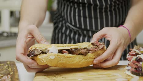 Chef-finishes-preparing-beef-sandwiches-on-wooden-cutting-board