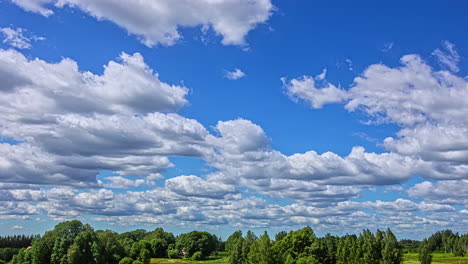 Geschwollene-Kumuluswolken-Schweben-Im-Blauen-Himmel,-Baumbedeckte-Landschaft