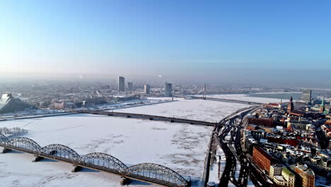 Aerial-view-of-Riga---bridges-crossing-the-frozen-Daugava-river,-Latvia