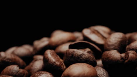 Close-up-shot-moving-around-heap-of-coffee-beans-with-black-background