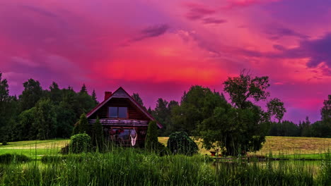 A-time-lapse-video-of-a-rural-hut-standing-alone-on-a-meadow-with-dynamic-pink-clouds-vividly-moving-in-the-background