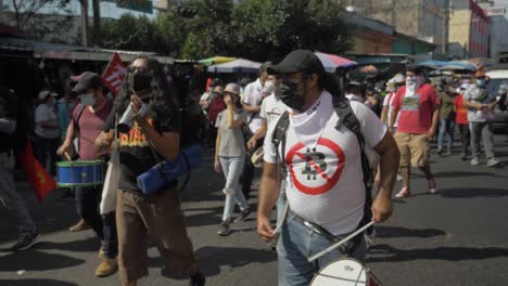 Musician-wearing-an-anti-bitcoin-shirt-plays-a-drum-on-the-streets-during-a-protest-agains-the-policies-of-current-president-Nayib-Bukele---Slow-motion