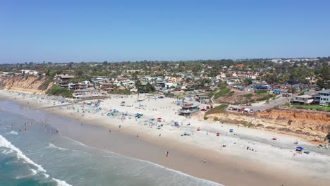 Aerial-view-of-a-busy-and-crowded-beach-at-summer-in-California,-America