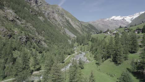 Video-Mit-Einer-Drohne,-Die-über-Den-Fluss-Lys-In-Einem-Alpental-Mit-Schneebedeckten-Bergen-Am-Horizont-Vorrückt-Und-Aufsteigt