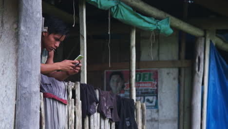 Junger-Amazonischer-Mann-Benutzt-Mobil,-Während-Wäsche-Trocknet