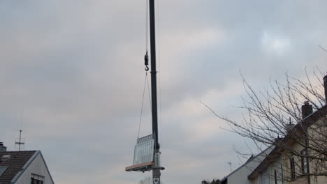 Truck-crane-slowly-lifts-a-frame-with-windows-over-a-multi-storey-residential-building