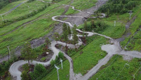 Downhill-mountain-bicycle-track-close-to-ski-lift-at-Ski-Geilo-Vestlia-Norway---Aerial-showing-downhill-track-with-no-people