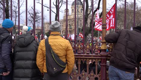 Leute-Hinter-Zaun-Blicken-Auf-Demonstranten-Gegen-Koronamaßnahmen-In-Wien