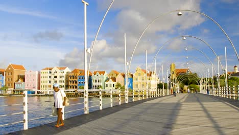 People-crossing-the-Queen-Emma-Bridge-over-Saint-Anna-Bay-in-the-picturesque-area-of-Punda,-Willemstad,-on-the-Caribbean-island-of-Curacao