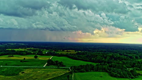 Stormy-heavy-clouds-are-floating-above-lush-green-fields-and-forests-in-rural-Latvia
