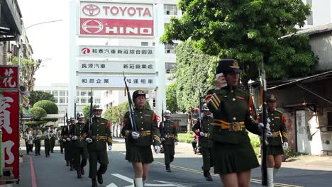 Asian-military-band-and-soldiers-with-bayonets-marching-on-streets-near-industrial-complex