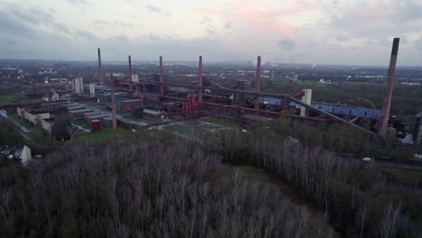 Flying-towards-Zeche-Zollverein-Coking-plant,-colorful-cloudy-pre-dawn