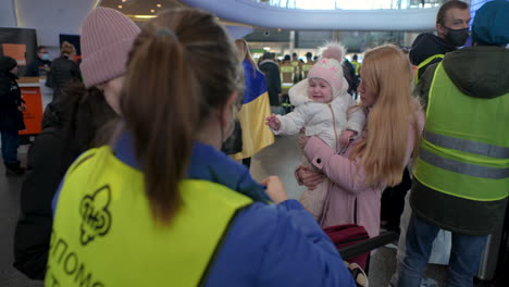 2022-Russian-invasion-of-Ukraine---Central-Railway-Station-in-Warsaw-during-the-refugee-crisis---young-volunteer-girl-is-helping-mother-and-child-with-some-information
